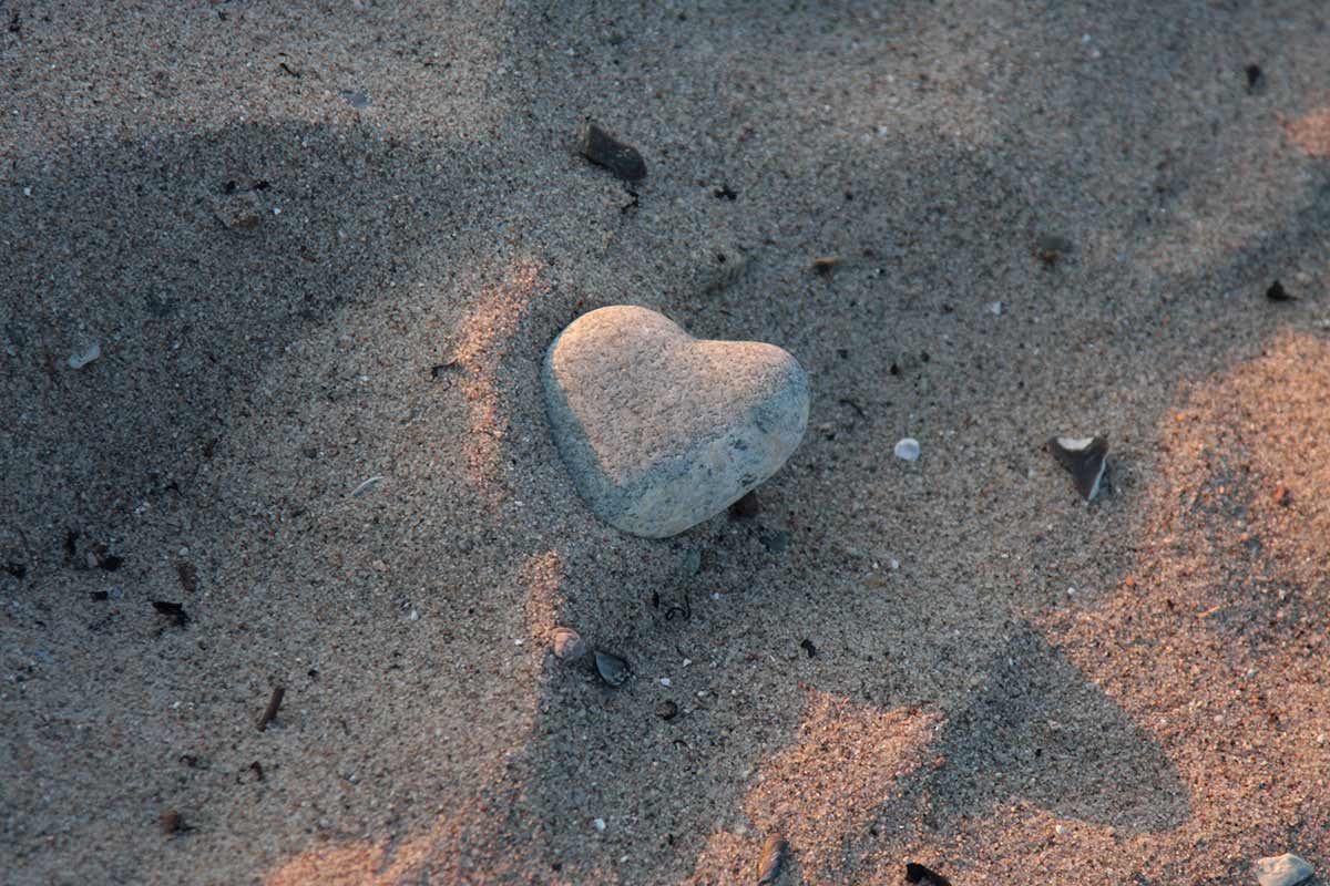 Stein als Herz geformt im Sand